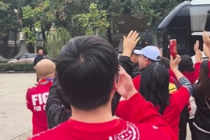 球迷夹道欢迎重庆铜梁龙球队大巴，并高举双手喊“重庆雄起！”